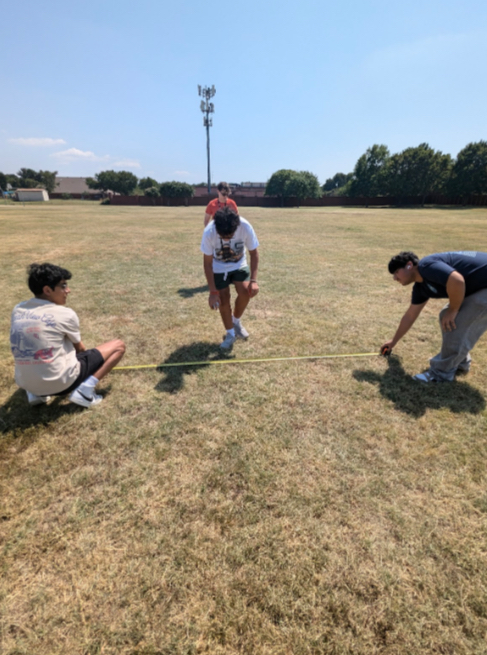 Bhavya Patel (11), Izyan Sultanali (11), and Sachman Oberoi (11) measuring the length of the line they are about to spray paint.